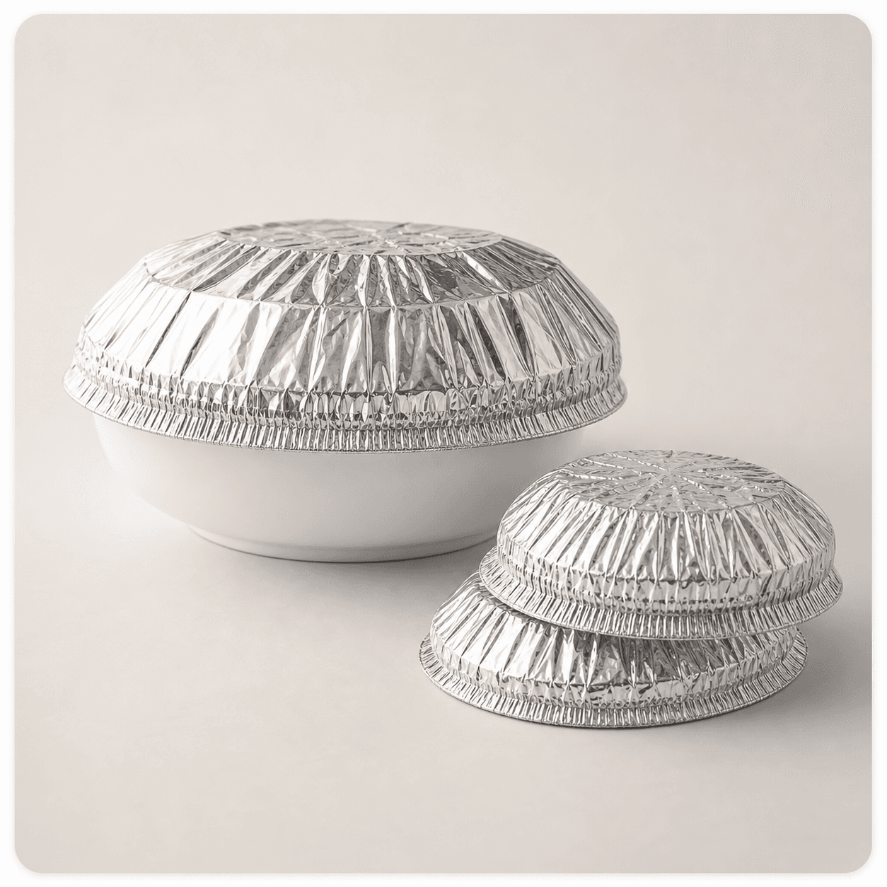 Premium silver aluminum foil dome food covers on a white ceramic bowl against a neutral studio background